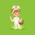 Sweet little girl with bunny ears and rabbit costume standing with basket full of painted eggs, kid having fun on Easter Royalty Free Stock Photo