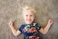 Sweet Little Girl Child in Flower Dress Laying on Carpet, Smilin
