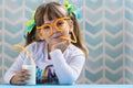 Sweet little girl drinking milk with funny glasses straw.