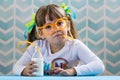 Sweet little girl drinking milk with funny glasses straw.