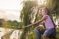 Sweet little girl and her mother spending fishing time near the river.