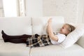 Sweet little girl lying on home sofa couch using internet app on digital tablet pad Royalty Free Stock Photo