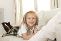 Sweet little girl lying on home sofa couch using internet app on digital tablet pad Royalty Free Stock Photo