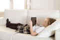 Sweet little girl lying on home sofa couch using internet app on digital tablet pad Royalty Free Stock Photo