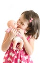 Sweet little girl in pink dress hold and kiss baby toy smiling i Royalty Free Stock Photo