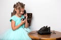 A little girl is ringing on the old phone.