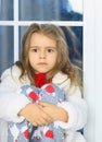 Sweet little girl sad at the window in pajamas for Christmas. Waiting for a miracle and gifts Royalty Free Stock Photo