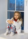 Sweet little girl sad at the window in pajamas for Christmas. Waiting for a miracle and gifts Royalty Free Stock Photo