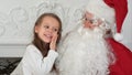 Sweet little girl on Santa Claus lap telling him what she wants for Christmas Royalty Free Stock Photo