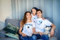 Sweet little girl together with beautiful young mom and dad sitting on sofa in living room at home in evening. Happy family Royalty Free Stock Photo