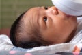 sweet little newborn asian baby drinking milk in plastic baby milk bottle relaxing on the bed and eyes contact to mother Royalty Free Stock Photo