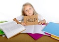 Sweet little school girl holding help sign in stress with books and homework