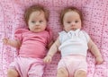 Sweet little twins lying on a pink blanket.