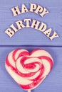 Sweet lollipop in shape of heart and inscription happy birthday on boards