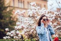 Young girl standing on Magnolia blossoming flowers tree Royalty Free Stock Photo