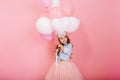 Sweet lovely moments of happy childhood with flying balloons of amazing pretty young girl in tulle skirt smiling to side