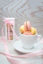 Sweet macaroons in cup and in gift box in wooden background, dessert concept Royalty Free Stock Photo