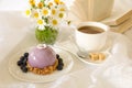 Sweet morning breakfast time concept, beautiful violet cake, blueberries, cup of tea near bouquet of chamomiles and open Royalty Free Stock Photo