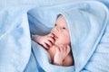 Sweet newborn baby boy in big blue towel after bath