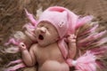 Sweet newborn baby in pink cap yawns and stretches, wakes Royalty Free Stock Photo