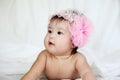 Sweet Newborn Baby in Pink Flower Hairband Lies on Bed