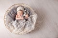 Sweet newborn baby sleeps in a basket. Beautiful newborn boy with bear toy. Copy space