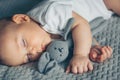 Sweet newborn baby sleeps with a gray toy hare on gray blanke Royalty Free Stock Photo