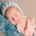 Sweet newborn in hat sleeping on woolen blanket