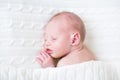 Sweet newborn sleeping baby under knitted blanket