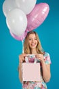 Sweet nice girl with baloons and little prersents bag in the hands on the blue background. Royalty Free Stock Photo