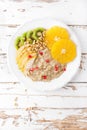 Sweet oatmeal porridge with pine nuts and fresh fruits - pear, orange, kiwi and pomegranate. Healthy dietary breakfast. Vegetarian Royalty Free Stock Photo