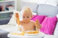 Sweet one years old baby boy, eating pasta at home, kid eats spaghetti Royalty Free Stock Photo