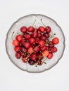 Sweet organic red cherries with water droplets in a glass bowl isolated on white background