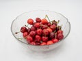 Sweet organic red cherries with water droplets in a glass bowl isolated on white background