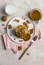 Sweet pancakes with boiled condensed milk and walnuts on plate with fork and knife, milk in glass and caramel in jar near, at Royalty Free Stock Photo