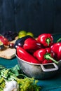 Sweet pepper in a round metal bowl and a bunch of basil in white textiles and wooden table from old vintage boards Royalty Free Stock Photo