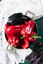 Sweet pepper in a round metal bowl and a bunch of basil in white textiles and wooden table from old vintage boards Royalty Free Stock Photo