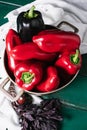 Sweet pepper in a round metal bowl and a bunch of basil in white textiles and wooden table from old vintage boards Royalty Free Stock Photo