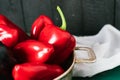 Sweet pepper in a round metal bowl and a bunch of basil in white textiles and wooden table from old vintage boards Royalty Free Stock Photo