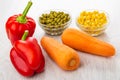 Sweet peppers, carrots, green peas and corn in bowls on table Royalty Free Stock Photo