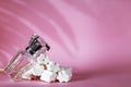 Sweet perfume bottle used almost empty on pink background. long shadows. copy space