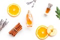 Sweet perfume with fruit fragrance. Bottle of perfume near apple, orange, lavender, cinnamon on white background to