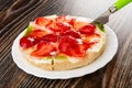 Sweet pie with strawberry and kiwi with table knife on plate on wooden table