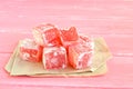 Sweet pieces of turkish delight on the wrapping paper and pink wood background Royalty Free Stock Photo