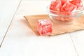 Sweet pieces of turkish delight on the wrapping paper and white wood background Royalty Free Stock Photo