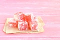Sweet pieces of turkish delight on the wrapping paper and wood background Royalty Free Stock Photo