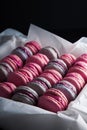 Sweet pink, violet french macaroon cookies in a box on black background