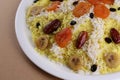 Sweet plov or pilaf with dried fruits and clarified butter on big white plate: eastern cuisine. Close up