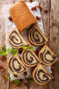 Sweet poppy cake with raisins, decorated with mint close-up on a wooden table. Vertical top view