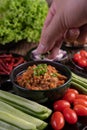 Sweet pork in a black bowl, complete with cucumbers, long beans, tomatoes, and side dishes